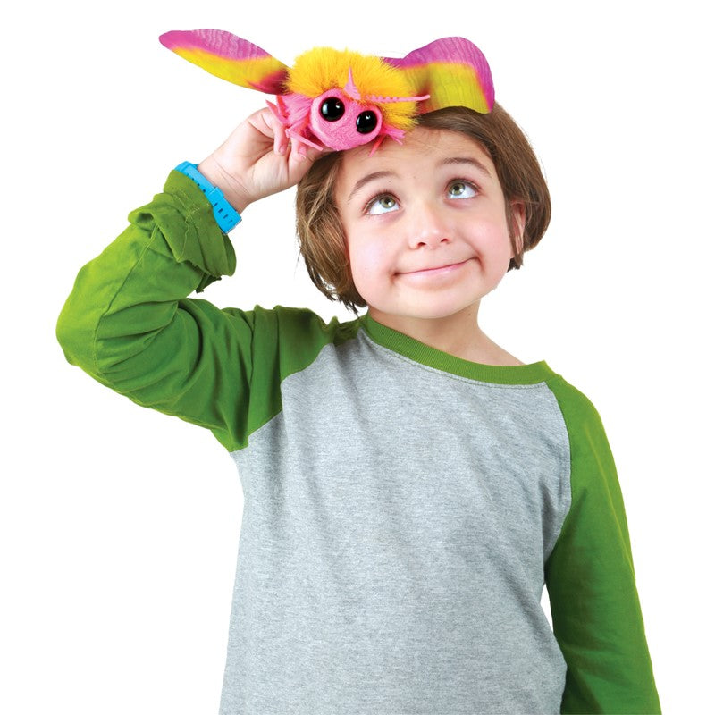 Child playing with a colorful Rosy Maple Moth Finger Puppet featuring big eyes and fuzzy pink and yellow wings.