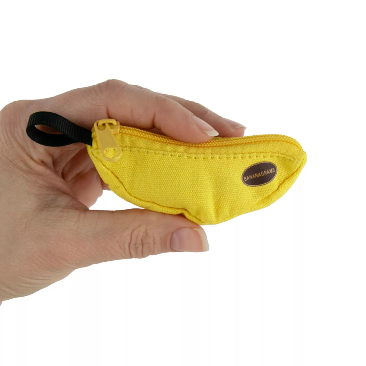 Hand holding the World's Smallest Bananagrams yellow banana-shaped pouch with zipper for portable word game tiles.