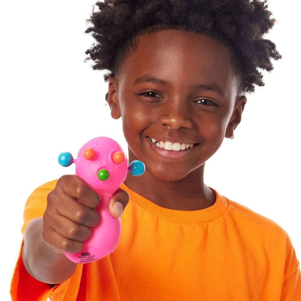 Child smiling and holding a bright pink NeeDoh Panic Pete stress toy with colorful pop-out features