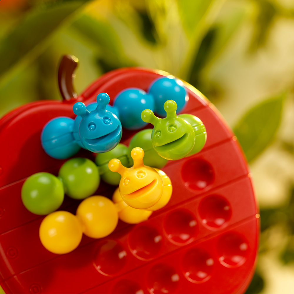 Apple Twist game board with colorful smiling caterpillar pieces arranged on red apple-shaped puzzle.