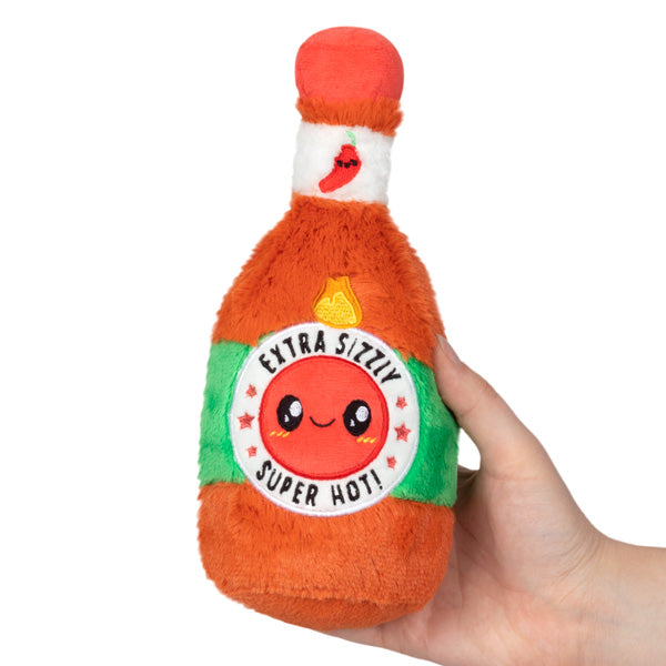 Hand holding Hot Sauce Snackers plush toy with smiling face and fiery pepper design, soft polyester fiber.