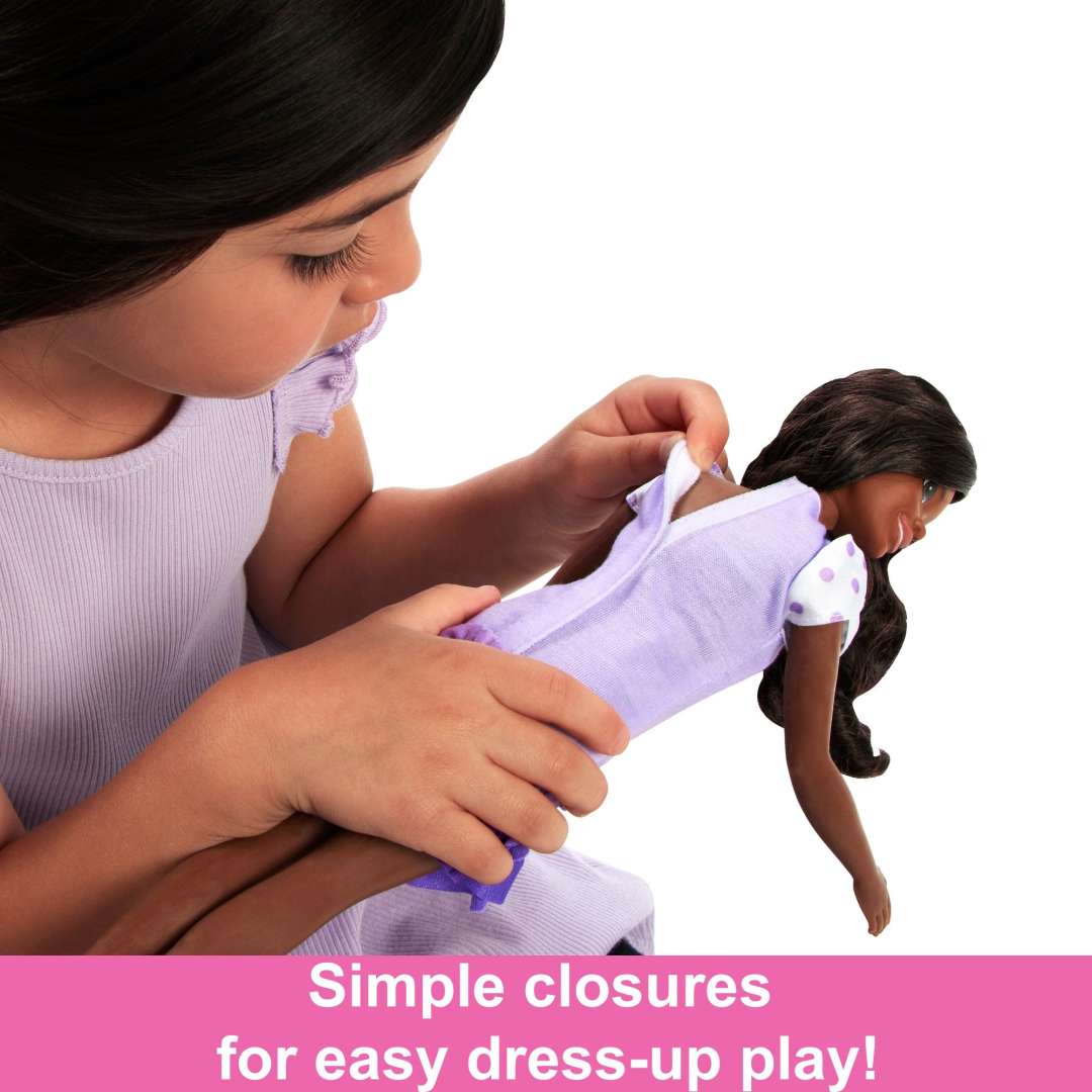 Child dressing the My First Barbie Black Hair doll in a lilac dress with easy closures for preschoolers.