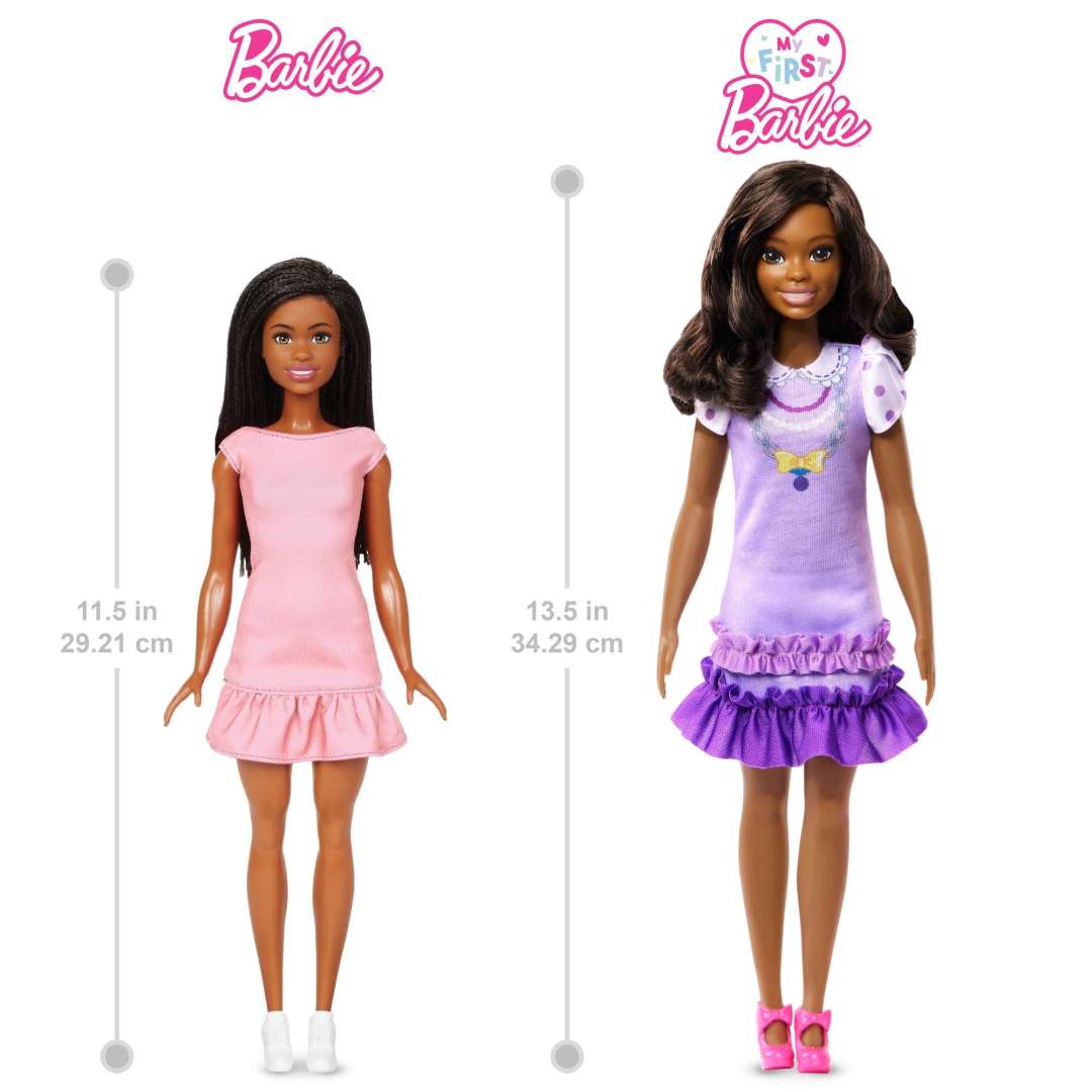 My First Barbie Black Hair doll wearing a lilac dress with ruffles and pink shoes, 13.5-inch poseable soft-touch body.