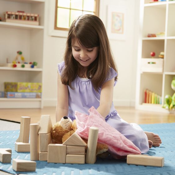 Girl playing with natural wooden blocks wooden blocks set on a blue mat in a bright room