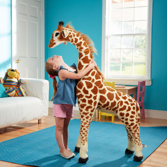 Giraffe BIG lifelike plush toy over 4 feet tall with realistic details, soft fabric, and wire-framed legs in a colorful playroom.