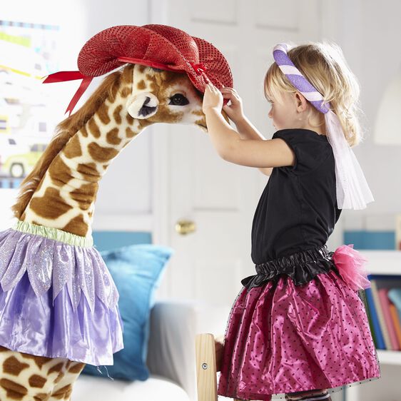 Giraffe BIG plush toy over 4 feet tall with realistic details, dressed in a purple skirt and red hat, interacting with a child.