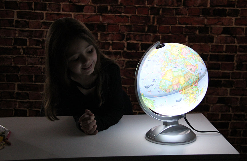 Kids Globe illuminated on a stand with a child looking, showing a kid-friendly educational globe with interactive features.