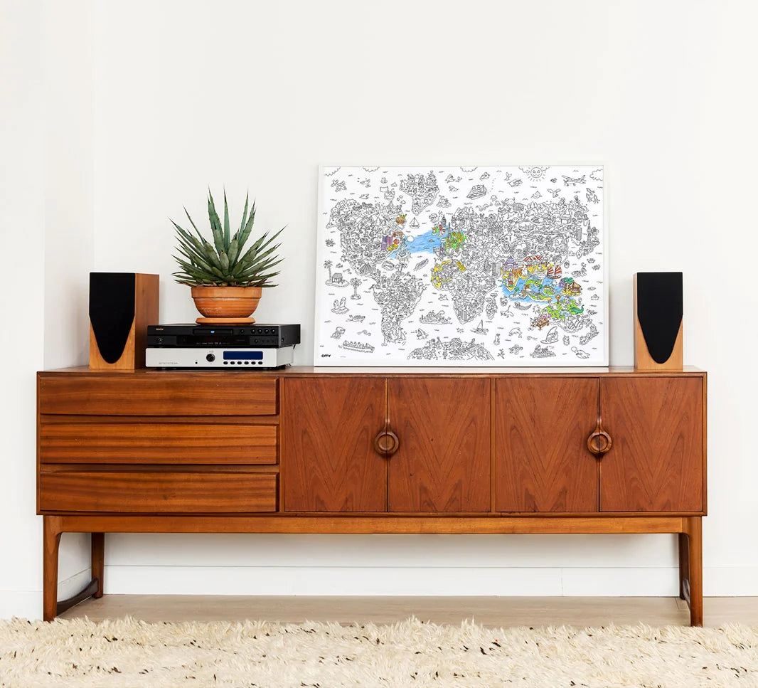 Atlas Giant Coloring Poster displayed on wooden cabinet with speakers and a potted plant in a cozy room setting.