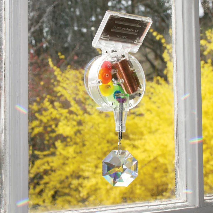 RainbowMaker solar-powered rainbow maker with genuine crystal hanging on window creating colorful light patterns.