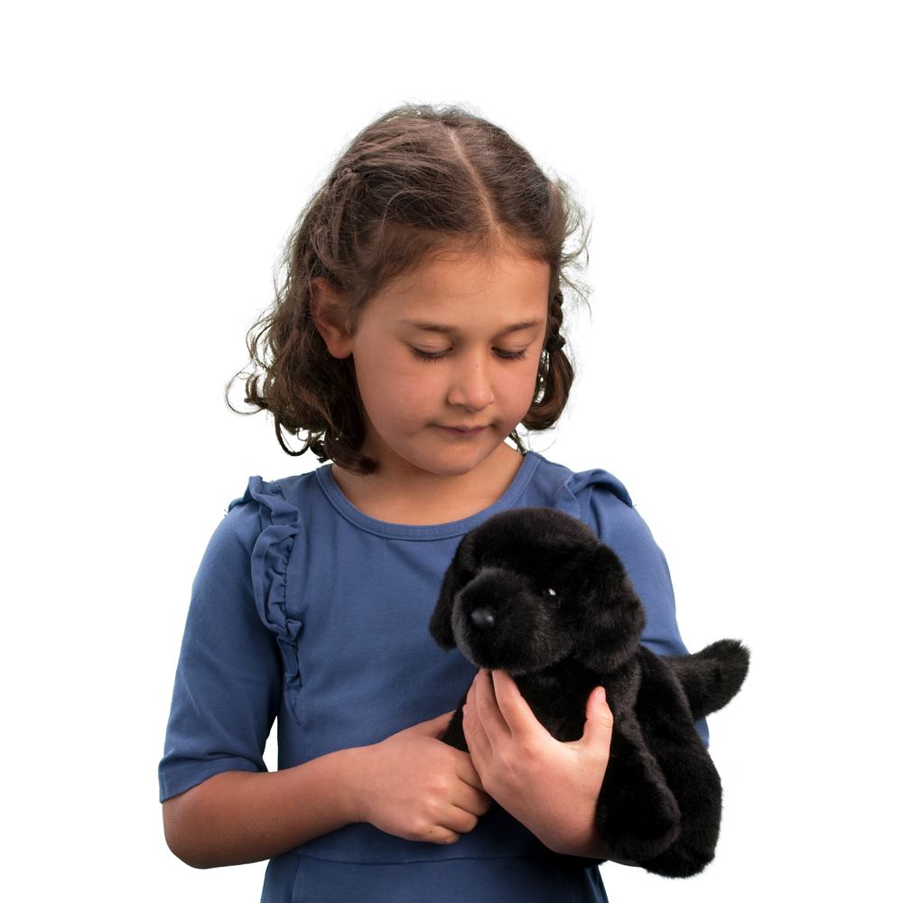 Child holding a soft plush toy Black Lab Bear with smooth black fur and loyal brown eyes.