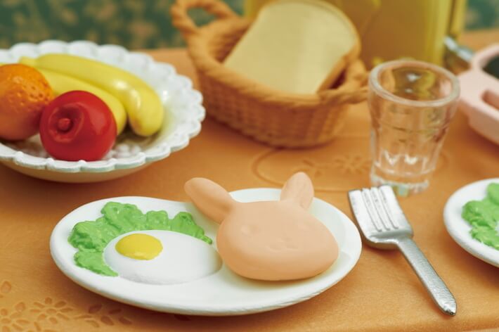Breakfast Playset showing a breakfast plate with fried egg, bunny-shaped bread, fruit, and a fork on an orange tablecloth.