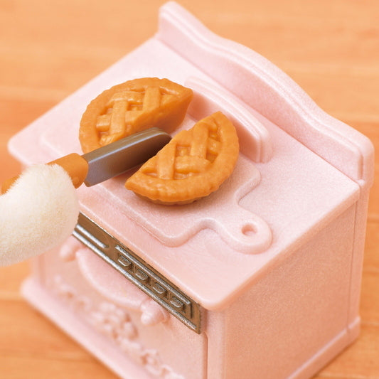 Playful Furniture showing a toy knife cutting a mini apple pie on a pink stove top for pretend play.