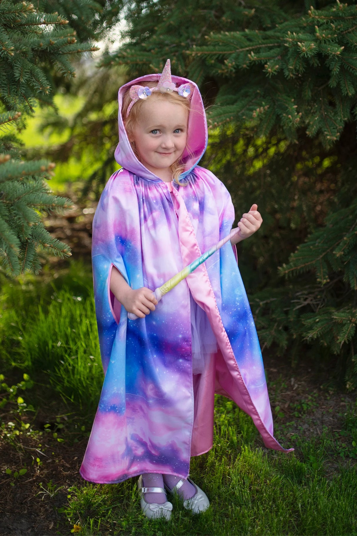 Young girl wearing a pastel unicorn cape holding the Magican Unicorn Wand with sparkly gem accents.