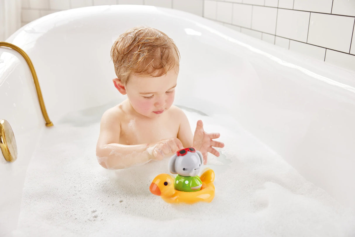 A toddler playing with the Swim n Splash Elephant toy in a yellow duck ring during bath time.
