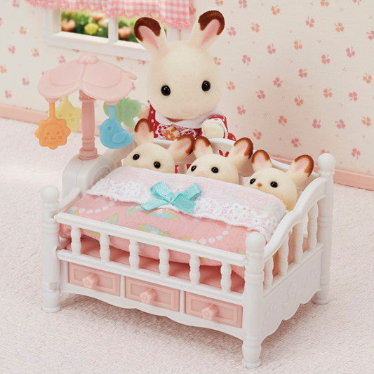 Crib with Mobile showing three baby triplets sleeping side by side under a pink blanket with rotating mobile.