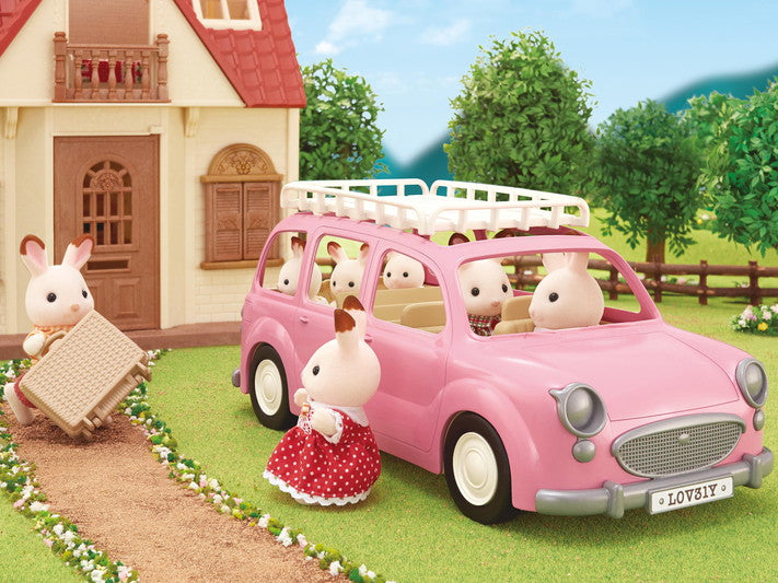 Pink Family Picnic Van toy with animal figures inside and outside near a dollhouse in a garden setting.