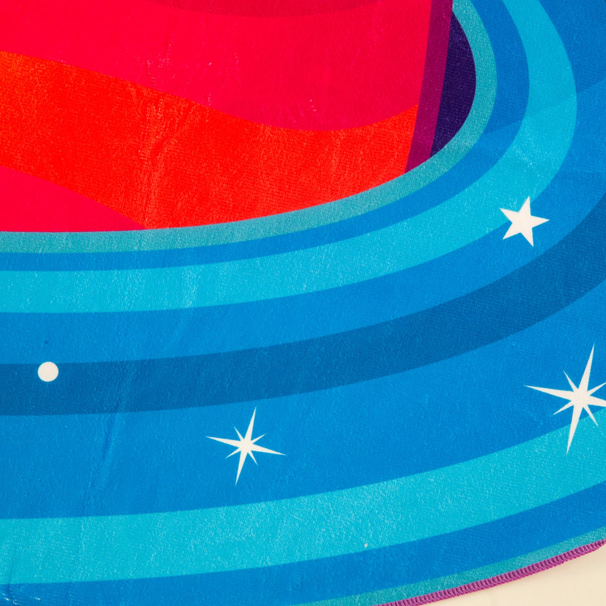 Close-up of the vibrant blue and red design on the ultra-soft Beach Blanket | Planet, perfect for outdoor relaxation.