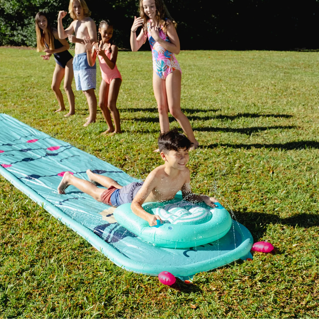 Children playing on the Splash Slide | Llama water slide with the matching bodyboard on a sunny day outdoors.