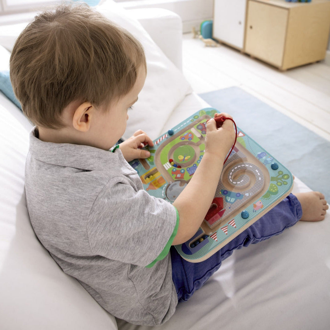 Child playing with Magnetic Puzzle Game | Town Maze, guiding colorful balls through a maze with a magnetic wand.