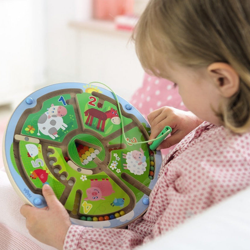 Child playing with Magnetic Maze Numbers toy featuring animals and colorful balls for number learning and motor skills.