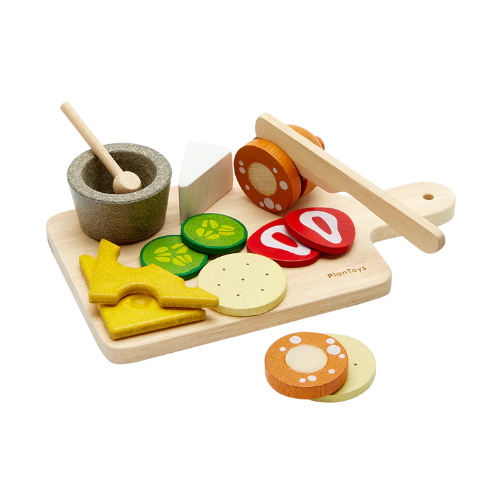Charcuterie Board with wooden cheese slices, pickles, salami, strawberries, knife, sauce cup, spoon, and cutting board set for kids.