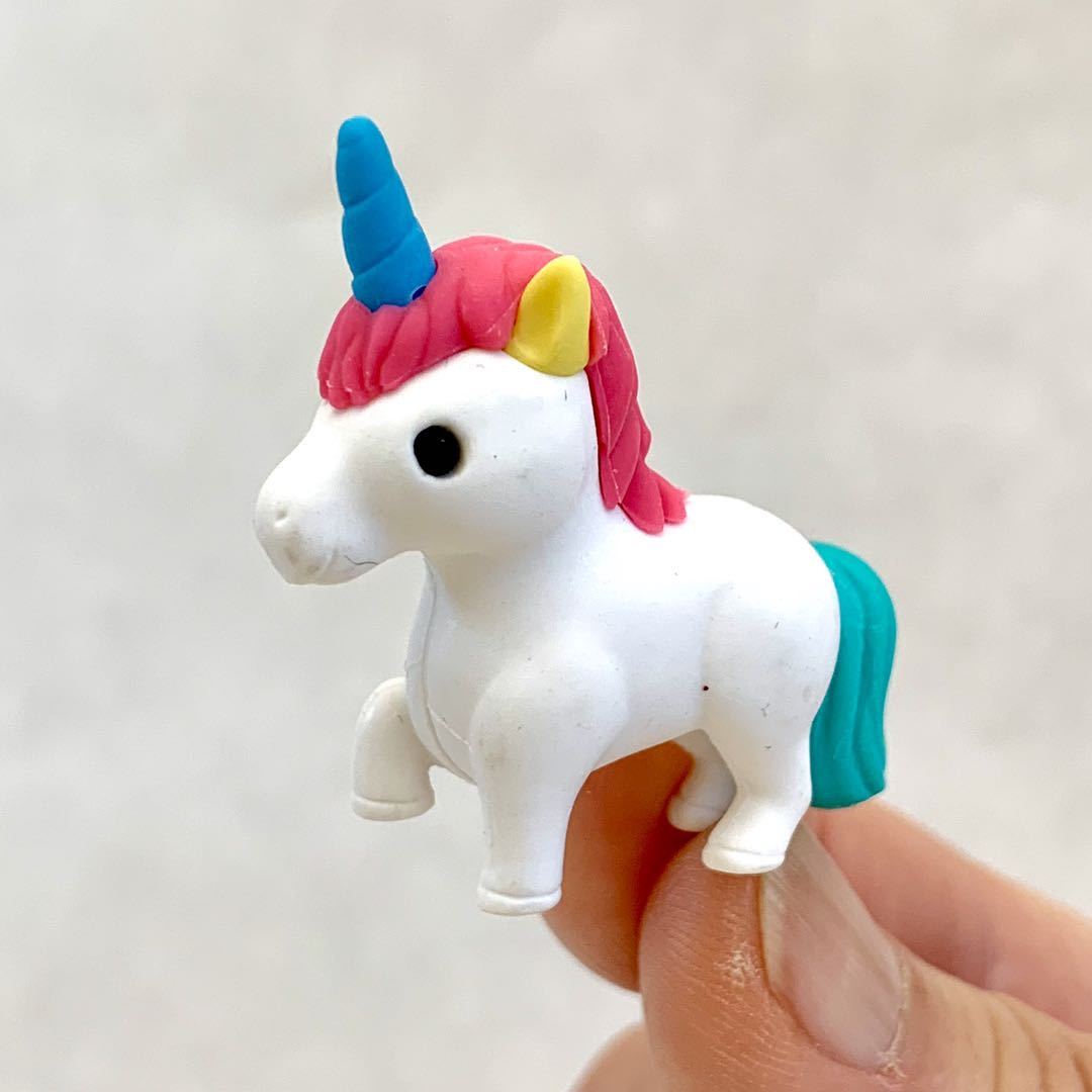 Hand holding a colorful Japanese Eraser Unicorn puzzle eraser with blue horn and pink mane close-up.