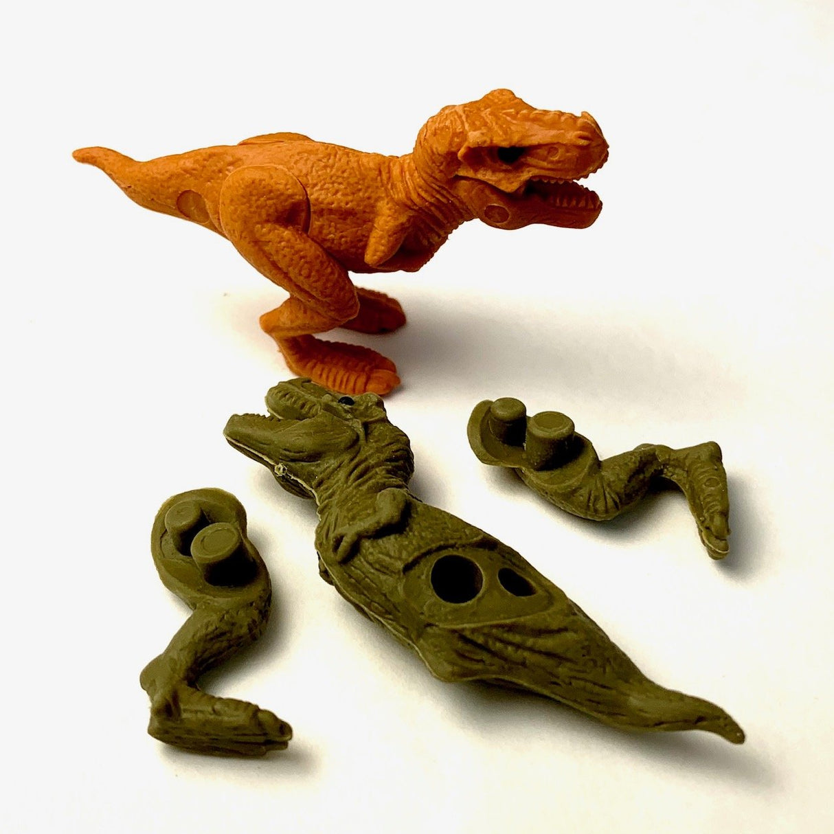 Japanese Eraser T-Rex puzzle with assembled orange dinosaur and disassembled green dinosaur pieces on white background.