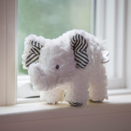 White plush elephant with striped ears sitting on a windowsill, Afrique Elephant Musical toy.