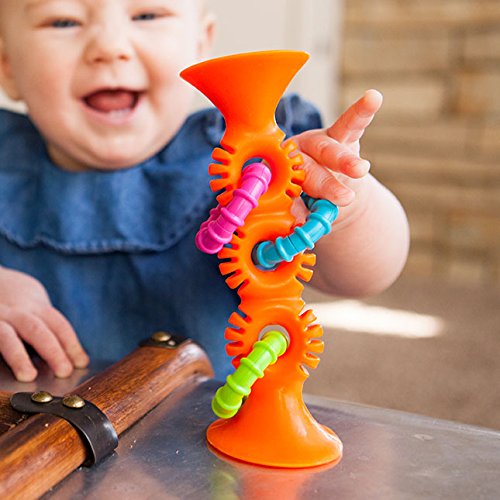 Baby playing with the bright orange pipSquigz Orange Loop sensory toy with colorful rattle rings on a table.