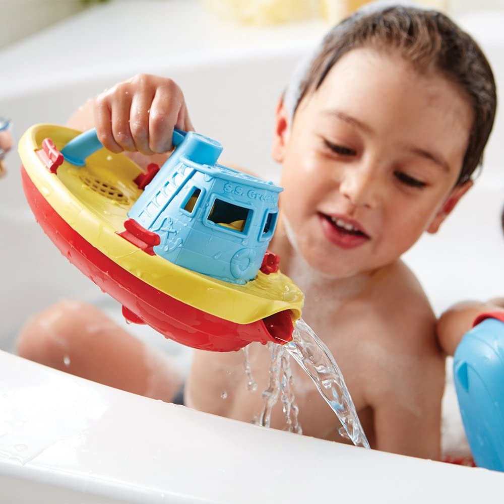 Child playing with a colorful Tugboat Watering Can pouring water in a bathtub, made from recycled plastic.