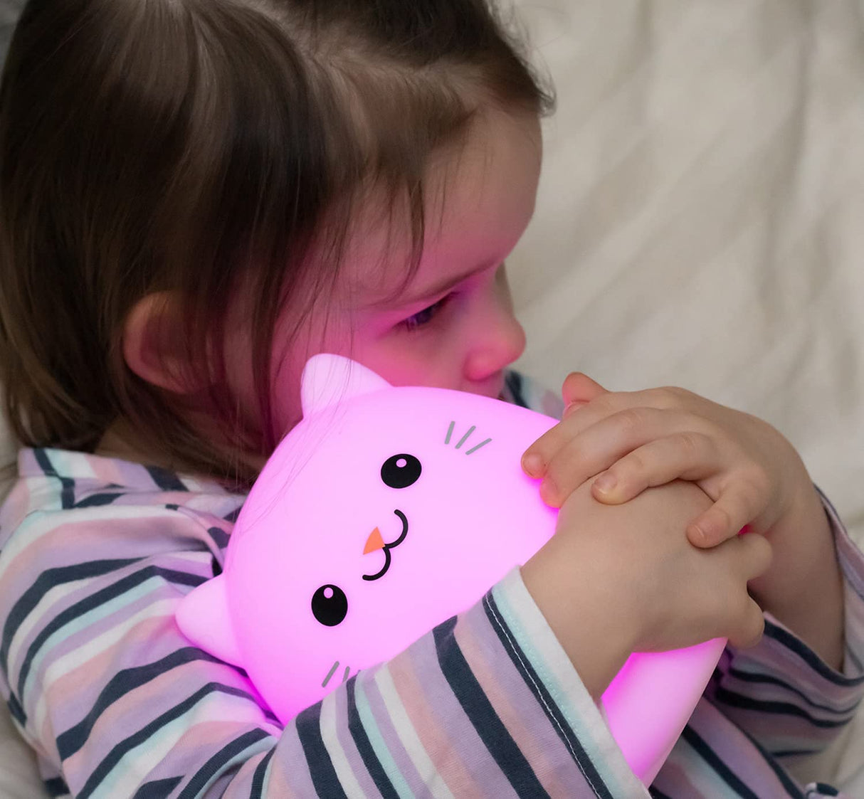 Child hugging a glowing pink cat-shaped LumiPets® LED Nightlight | Cat with soft silicone light.