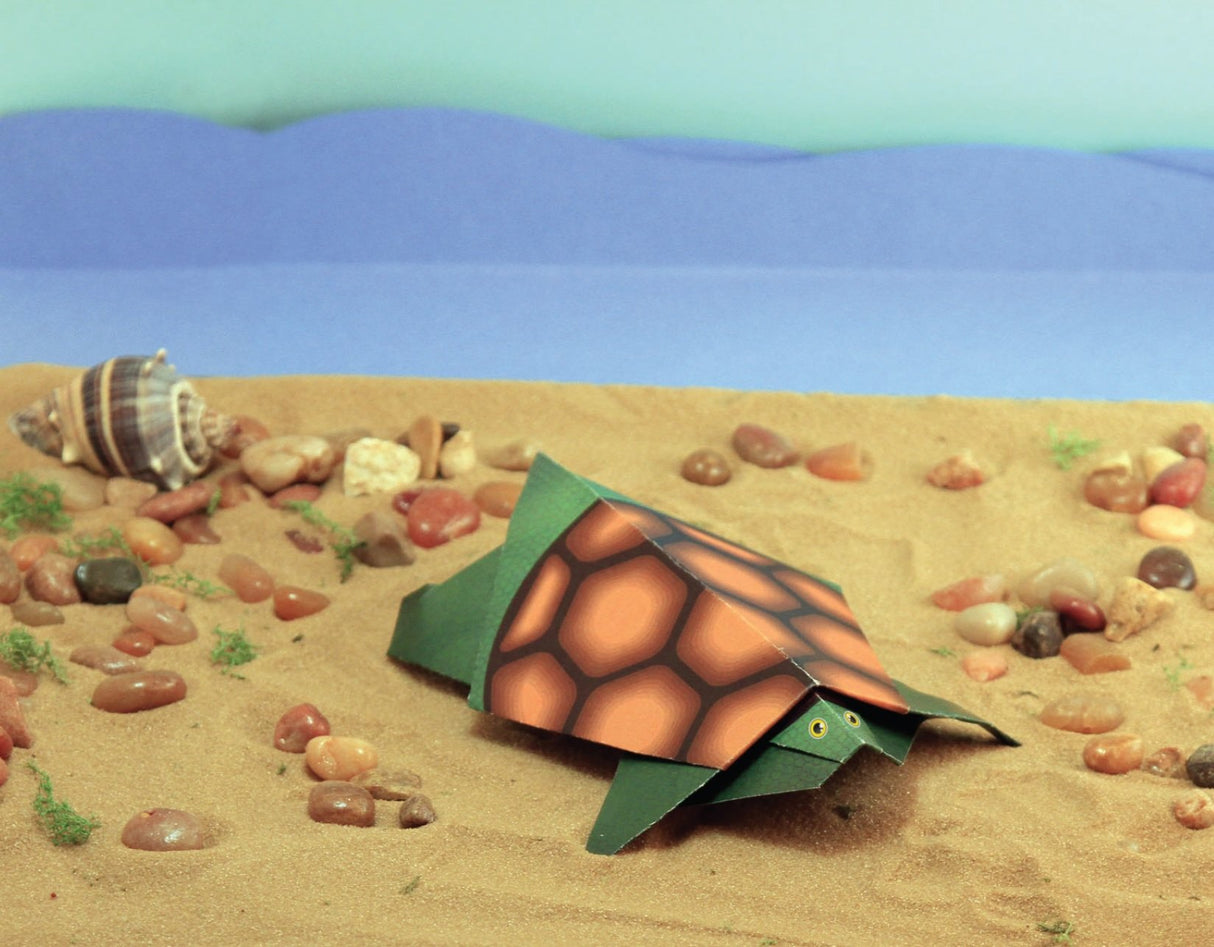My First Origami Kit featuring a detailed paper turtle with textured folding sheets on a sandy beach scene.