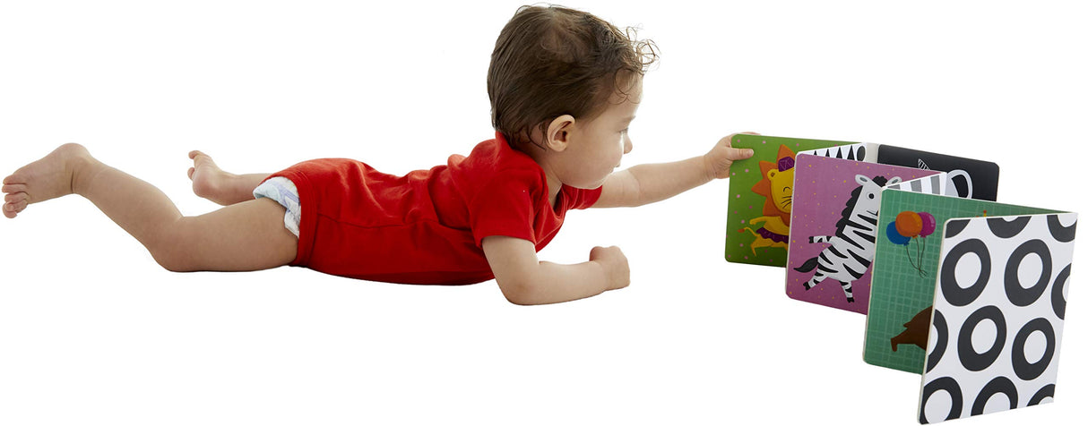Baby lying on tummy reaching for colorful fold-out TummyTime Animal Parade book with animals and black-and-white patterns.