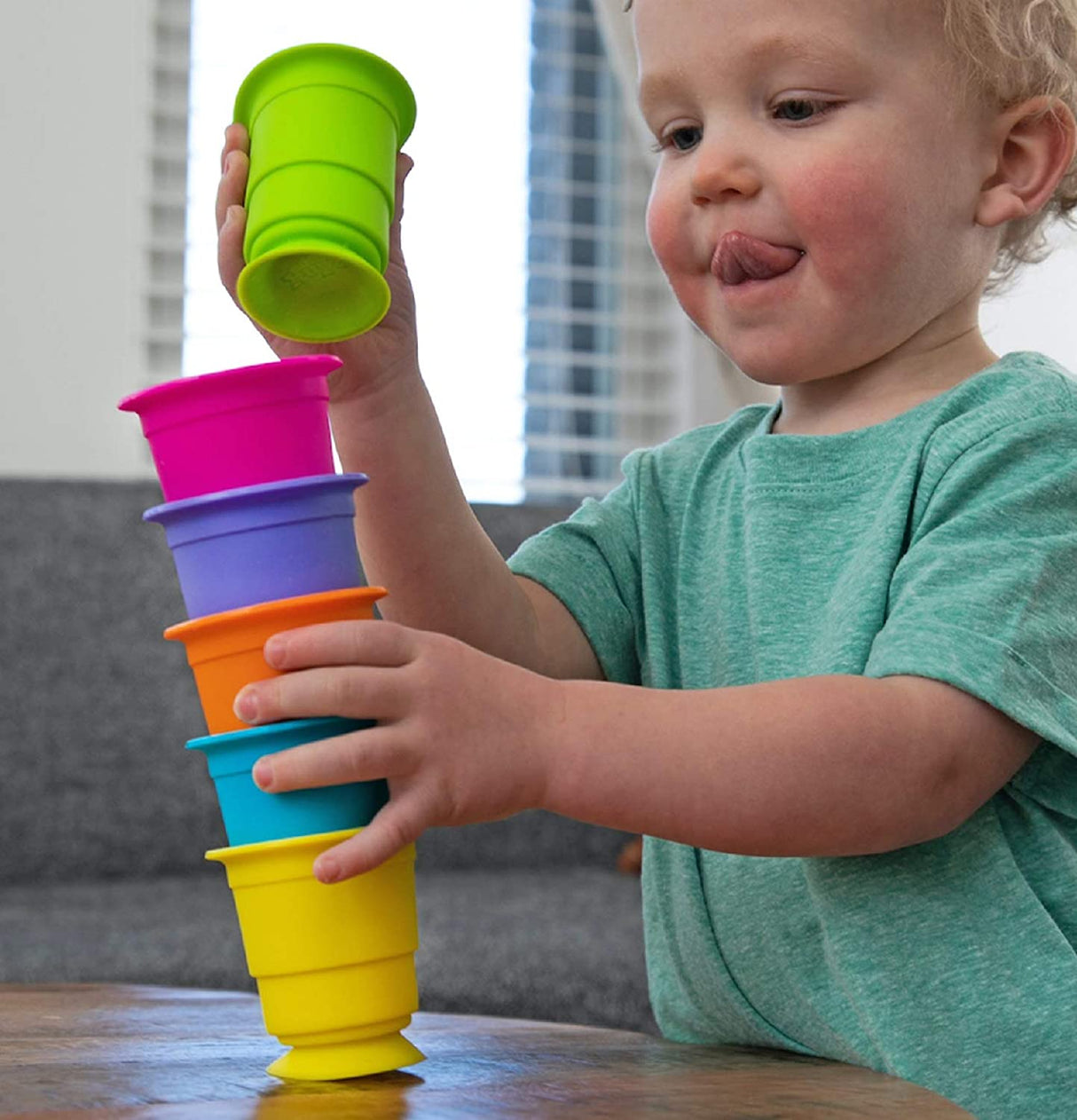Young child stacking colorful silicone cups with suction bases, playing with Suction Kupz for creative fun.
