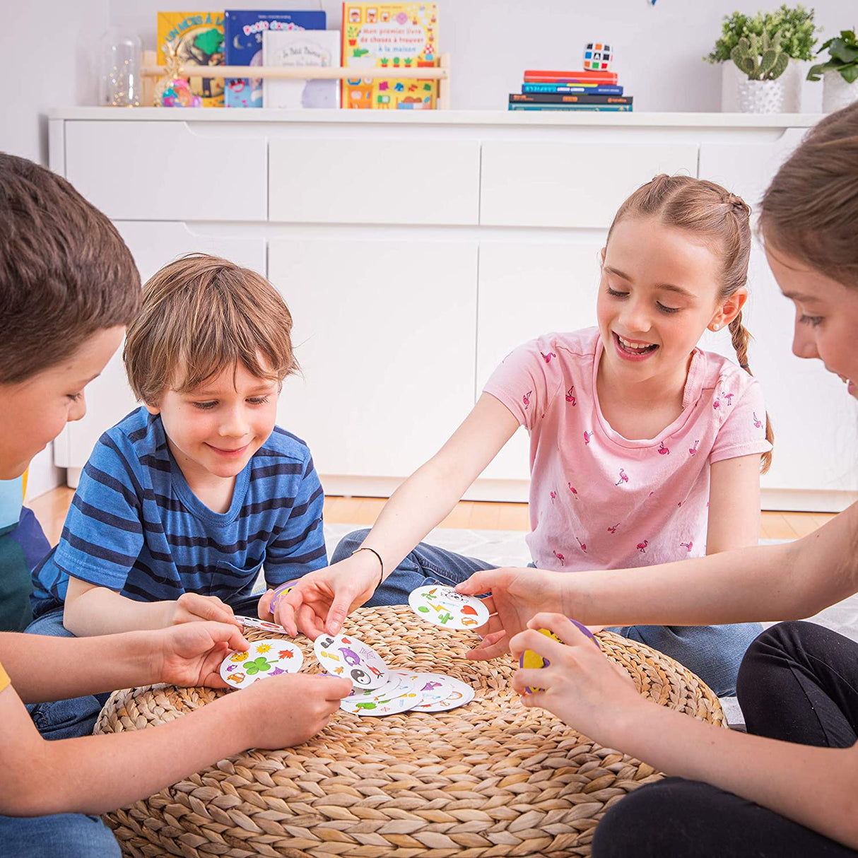 Children playing Spot it! card game together on a woven mat, enjoying this fast-paced matching game.