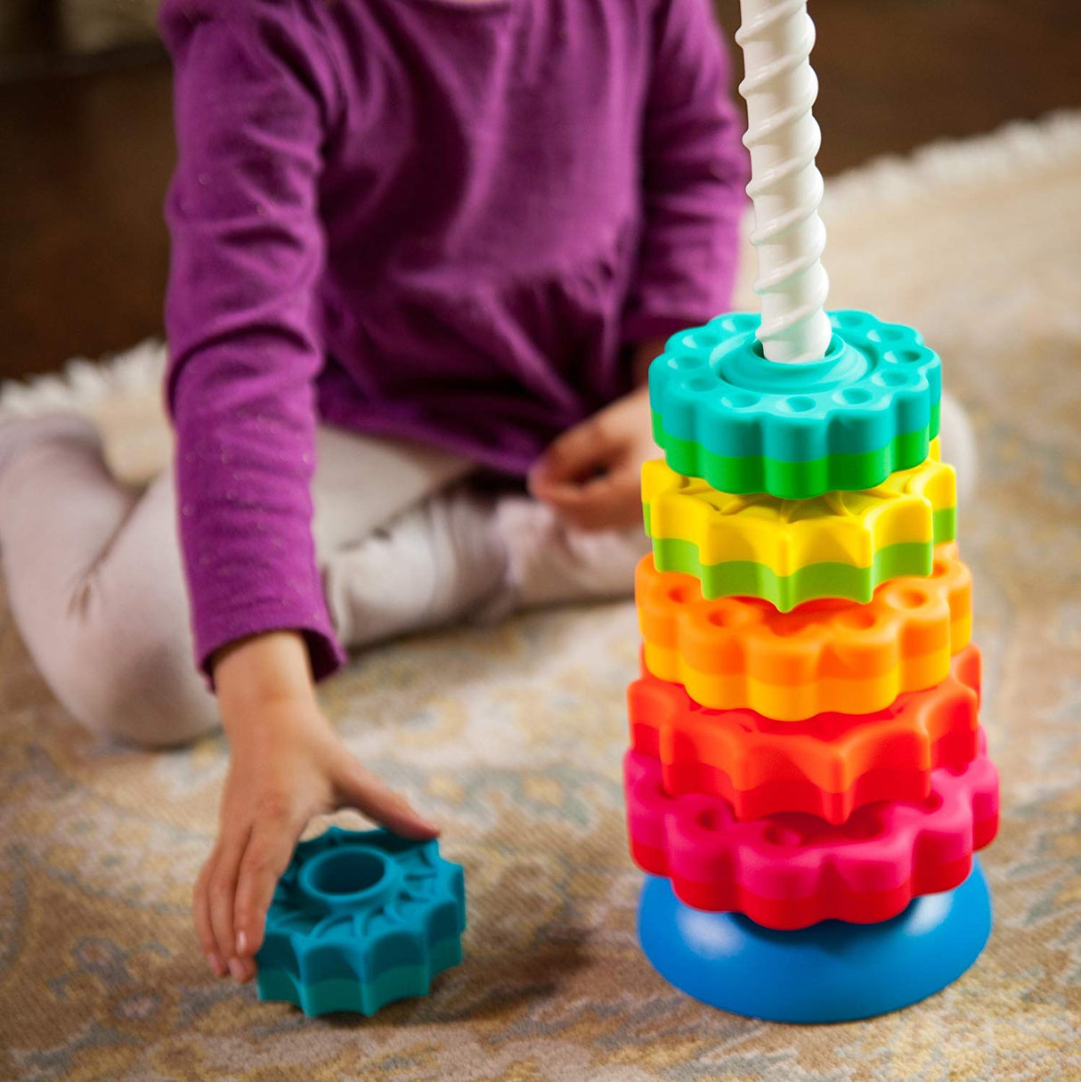 SpinAgain stacking toy with colorful star and daisy discs spinning on a white corkscrew pole and reversible base.