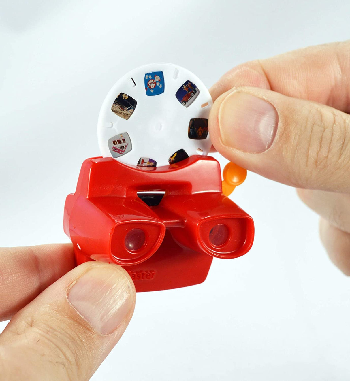 Hands holding the World's Smallest Viewmaster with a 7-image reel being inserted for retro viewing fun.