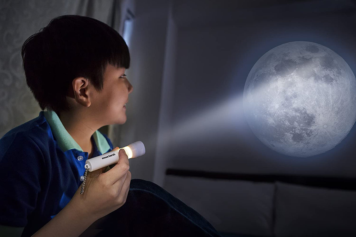 Young boy shining the Moon Torch Light on a wall at night to project a realistic moon image indoors.