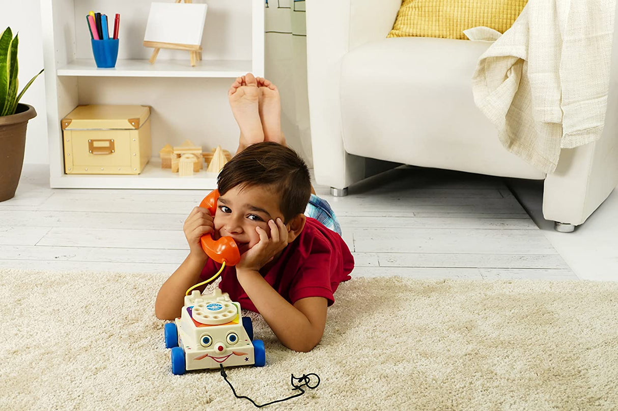 Child playing with a Fisher Price Chatter Phone pull toy with rolling eyes and rotary dial on a carpet.