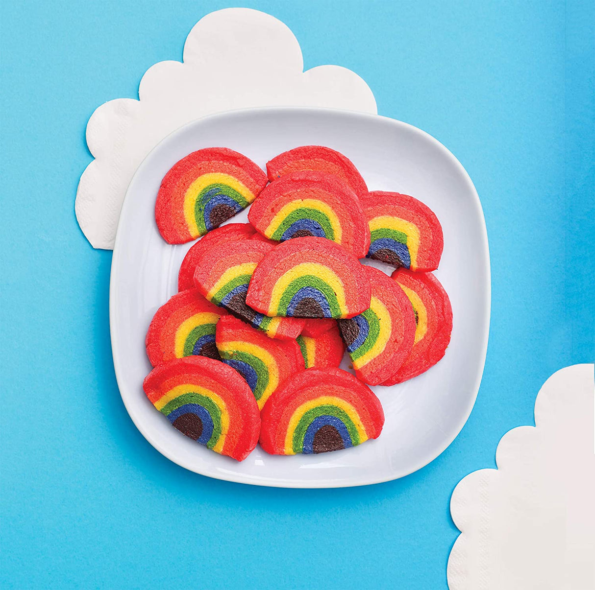 Kids Magical Baking rainbow cookies displayed on white plate with blue background and cloud decorations.