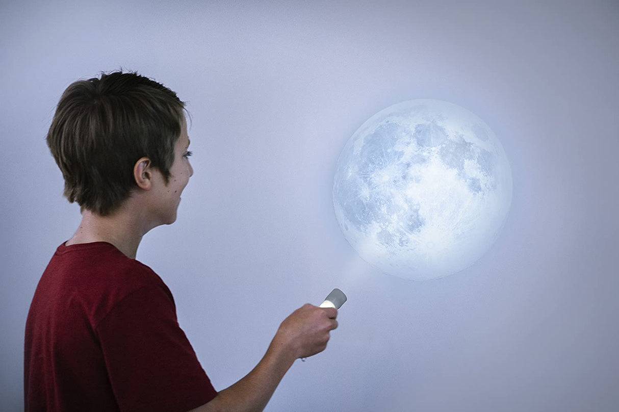 Boy shining Moon Torch Light to project a detailed moon image on a wall in a dark room at night.