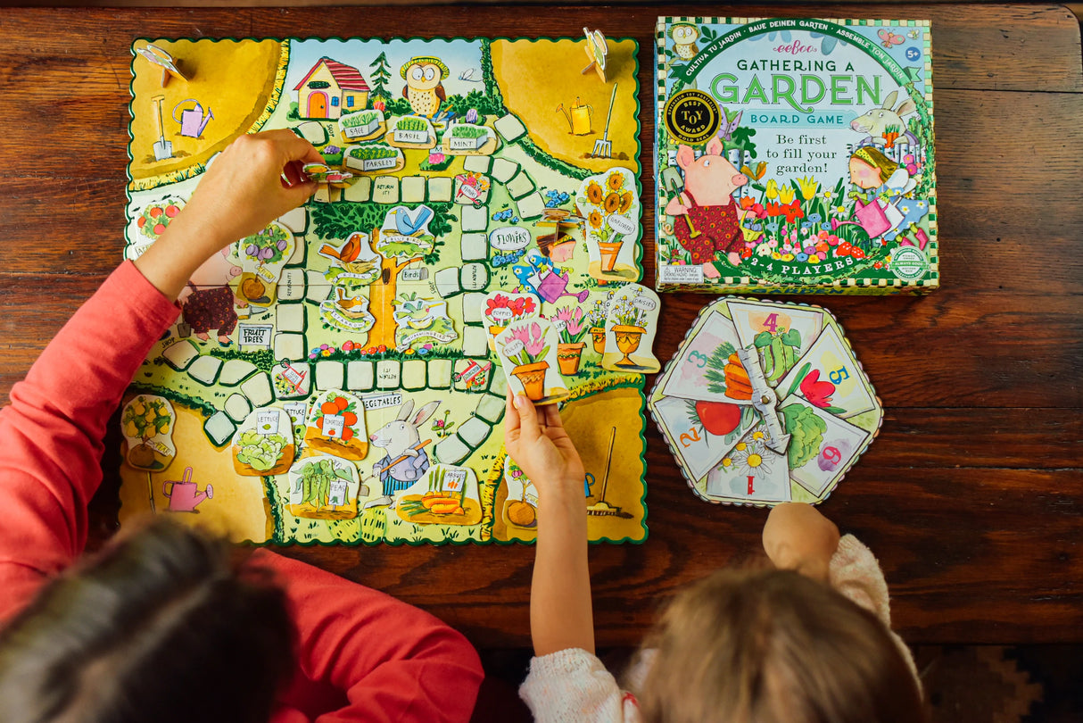 Gathering A Garden board game with children playing, colorful garden-themed pieces, spinner, and illustrated game box.