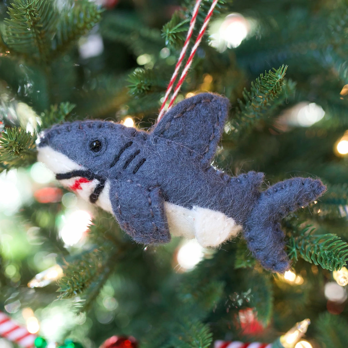 Shark Felt Ornament handmade from colorful sheep wool, hanging on a Christmas tree with a red string.