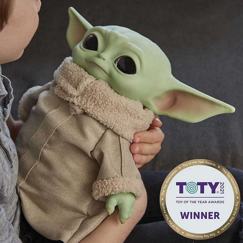 Star Wars The Child plush held by a child, soft green character with large ears and cozy beige outfit.