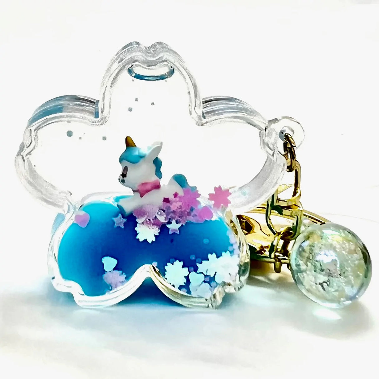 Unicorn Flower Keychain with a blue base, clear flower-shaped frame, and a small unicorn figure inside.