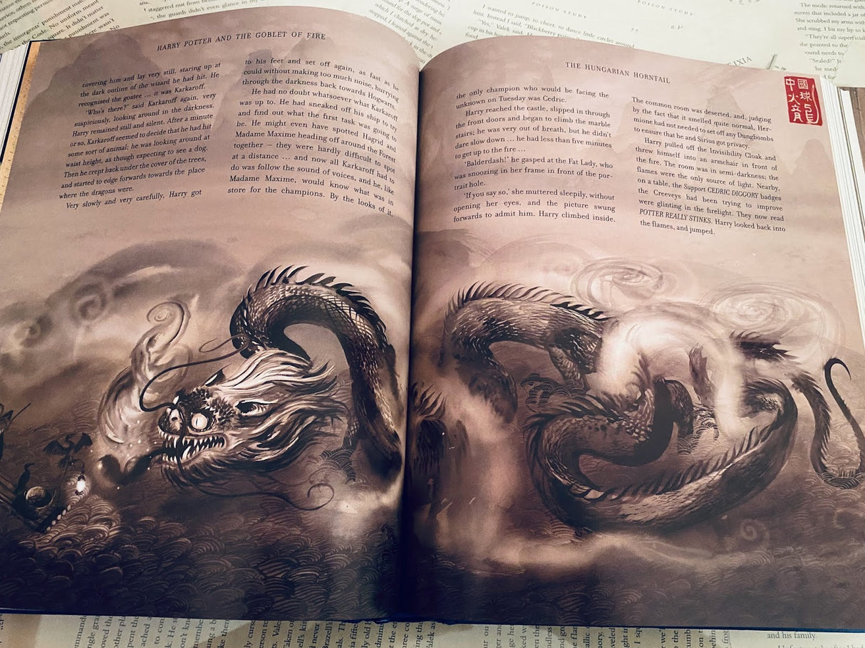 Open pages of Harry Potter and the Goblet of Fire Illustrated Edition showing detailed dragon artwork in sepia tones.