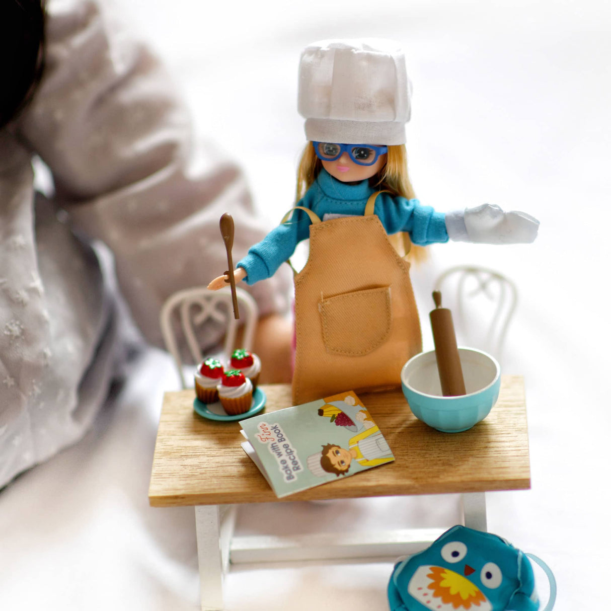 Lottie Cake Bake Outfit with chef hat, apron, oven mitt, mixing bowl, rolling pin, cupcakes, and recipe book.