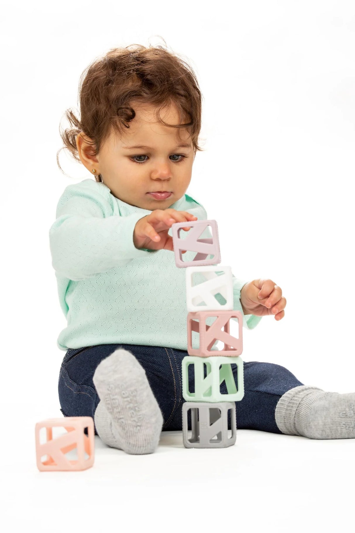Baby stacking pastel cubes while playing with Stack & Chew Pastel Cubes developmental teething toy for motor skills.