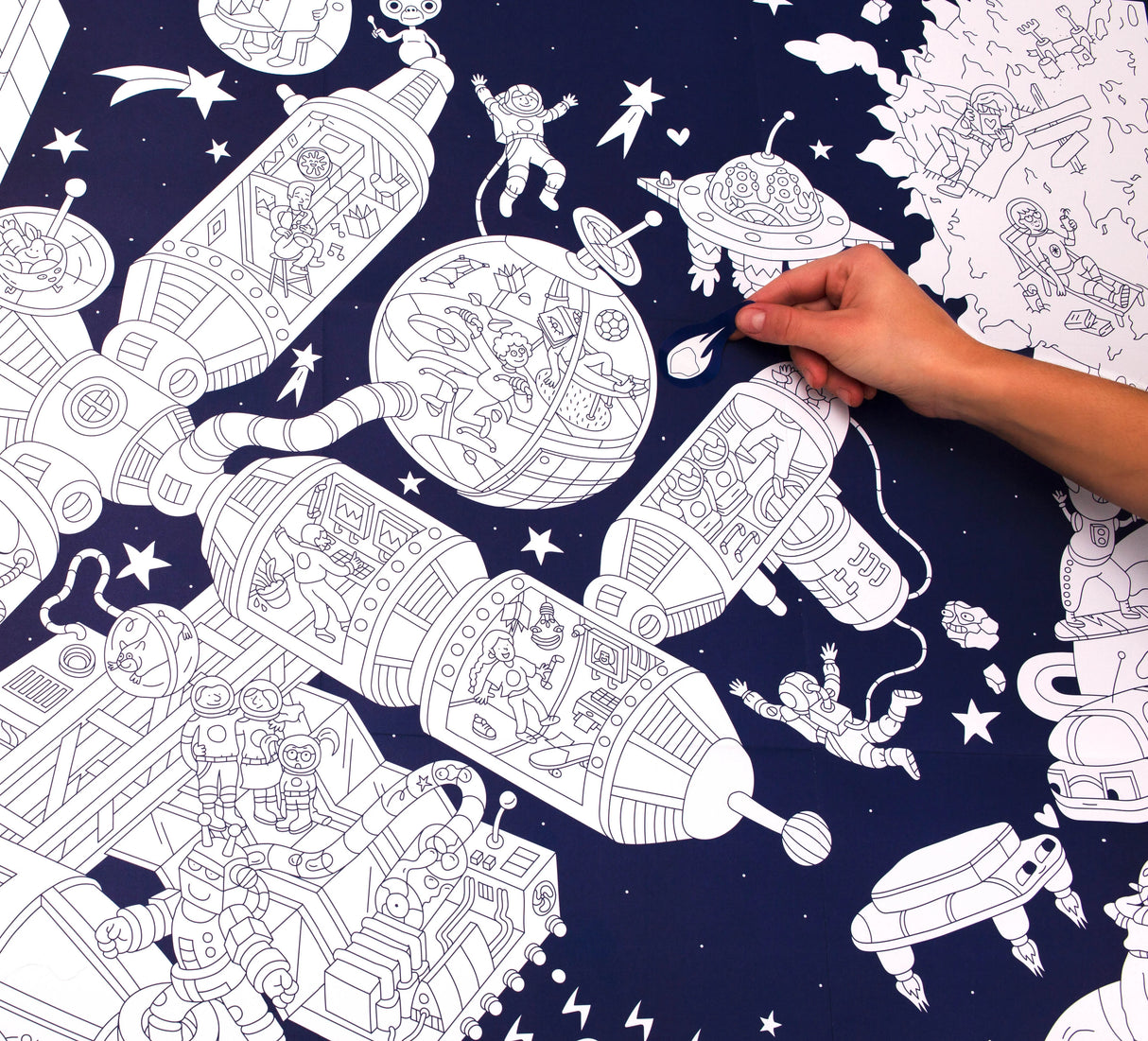 Space Giant Coloring Poster With Stickers showing a hand coloring a detailed space station scene with astronauts and UFOs.