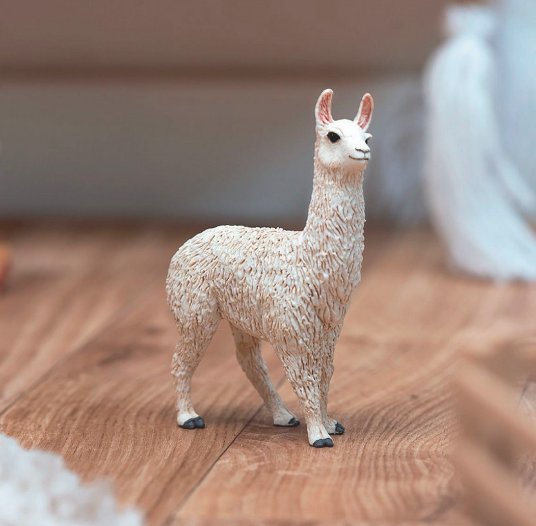 Llama figurine from Schleich FARM WORLD with detailed white wool standing on wooden surface for kids.
